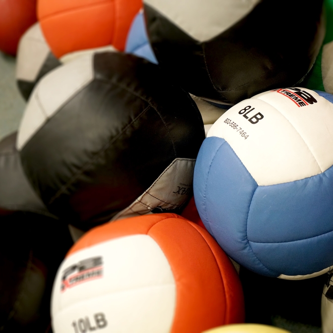 Pile of colorful stitched exercise balls on gym floor.