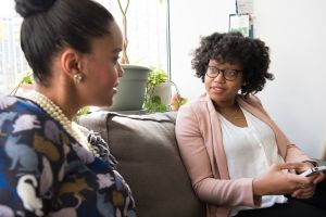 Two women sitting on couch speaking with each other