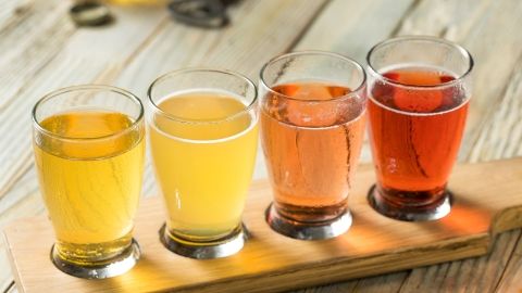 row of small glasses containing different color liquids on a wood tray