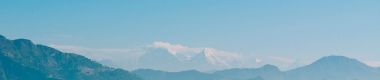 A landscape of a field, mountains and blue sky